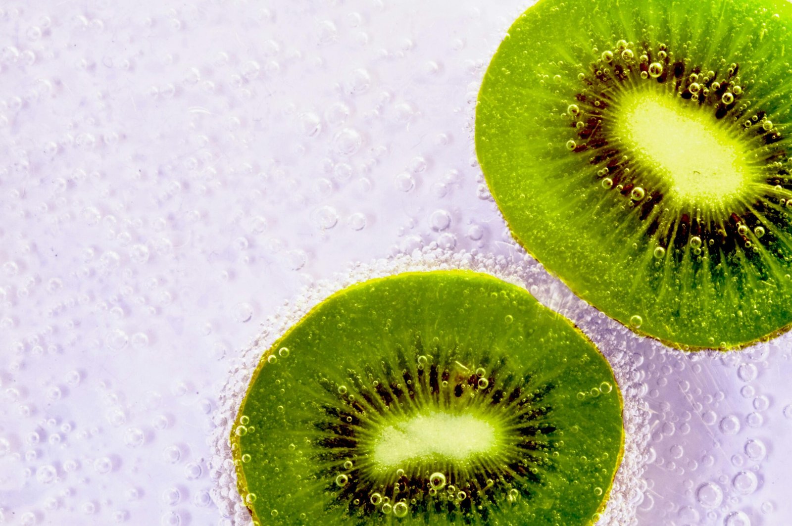 Close-up of fizzy kiwi slices in sparkling water, showcasing freshness and vibrant color.